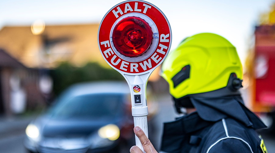 Ein Mitglied der Feuerwehr hält eine Kelle mit der Aufschrift «Halt Feuerwehr» in die Höhe. / Foto: David Inderlied/dpa/Symbolbild