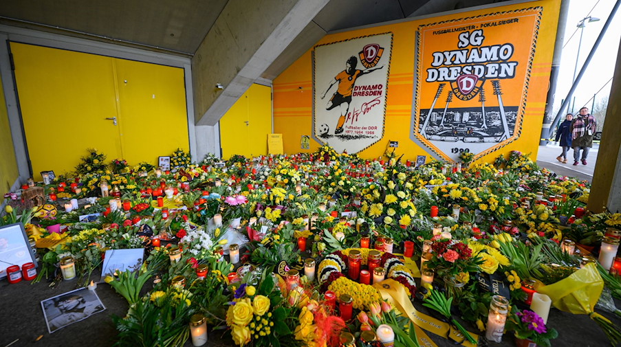 Zahlreiche Blumen, Kerzen, Fotos und Fan-Utensilien stehen zum Gedenken an den verstorbenen ehemaligen Spieler der SG Dynamo Dresden, Hans-Jürgen „Dixie“ Dörner, im Rudolf-Harbig-Stadion. / Foto: Robert Michael/dpa-Zentralbild/dpa