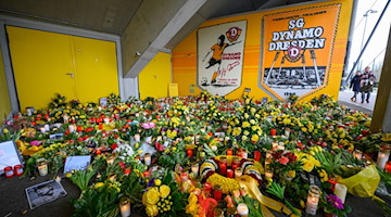 Zahlreiche Blumen, Kerzen, Fotos und Fan-Utensilien stehen zum Gedenken an den verstorbenen ehemaligen Spieler der SG Dynamo Dresden, Hans-Jürgen „Dixie“ Dörner, im Rudolf-Harbig-Stadion. / Foto: Robert Michael/dpa-Zentralbild/dpa