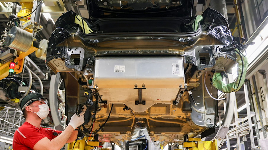 Ein Mitarbeiter montiert den Akku in einen Porsche Panamera Hybrid im Leipziger Porsche Werk. / Foto: Jan Woitas/dpa-Zentralbild/dpa/Bildarchiv