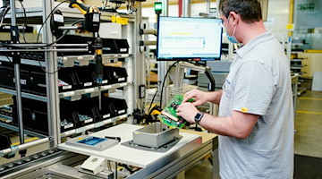 Ein Mitarbeiter montiert im Stammwerk eines Maschinenbauers ein Ladegerät. / Foto: Uwe Anspach/dpa/Archivbild