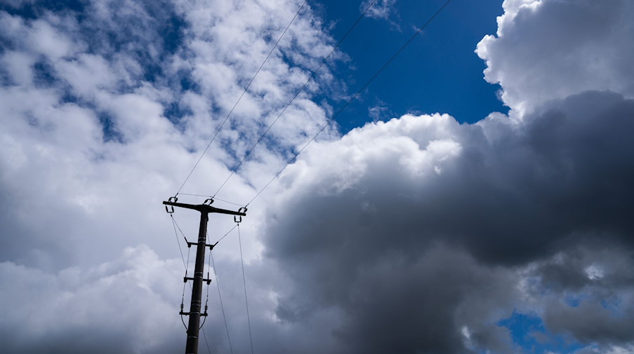 Ein Strommast hebt sich vor dem stark bewölkten Himmel ab. / Foto: Nicolas Armer/dpa/Symbolbild
