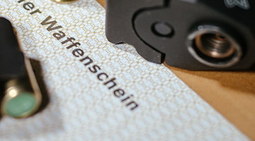 Ein Kleiner Waffenschein liegt zwischen einer Schreckschuss-Pistole, einem Magazin und einer Patrone. / Foto: Oliver Killig/dpa-Zentralbild/dpa/Illustration