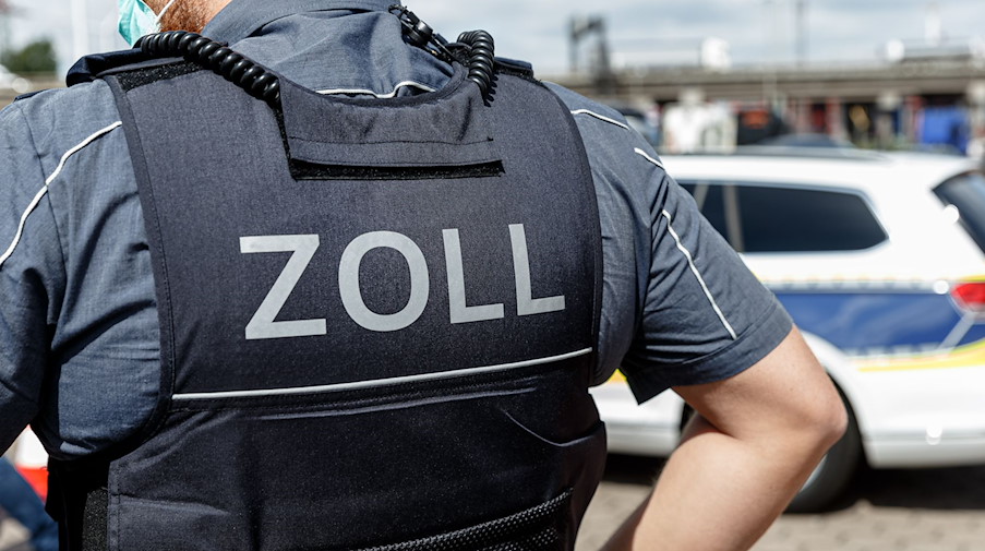 Ein Beamter trägt während seines Dienstes eine Schutzweste mit der Rückenaufschrift «Zoll». / Foto: Markus Scholz/dpa/Symbolbild