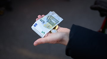 Eine Frau hält das Bargeld für ihren Einkauf in der Hand bereit. / Foto: Jonas Walzberg/dpa/Symbolbild
