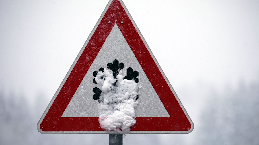 Ein Verkehrsschild, auf dem vor Schnee- und Eisglätte gewarnt wird, ist mit Schnee bedeckt. / Foto: Karl-Josef Hildenbrand/dpa/Symbolbild
