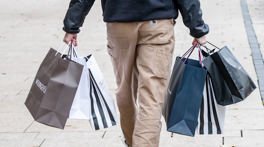 Ein Mann geht mit Einkaufstüten durch die Innenstadt. / Foto: Markus Scholz/dpa/Symbolbild