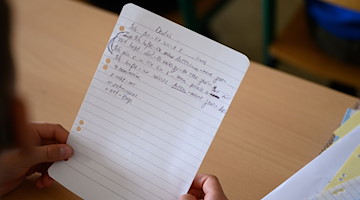 Ein Grundschüler aus der Ukraine hält in der einen Zettel mit Schreibübungen in der Hand. / Foto: Robert Michael/dpa
