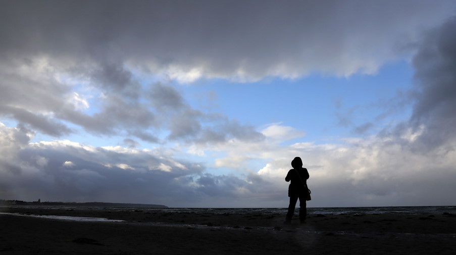 Ein Spaziergänger schaut auf den wolkigen Himmel. / Foto: Bernd Wüstneck/dpa-Zentralbild/dpa/Symbolbild