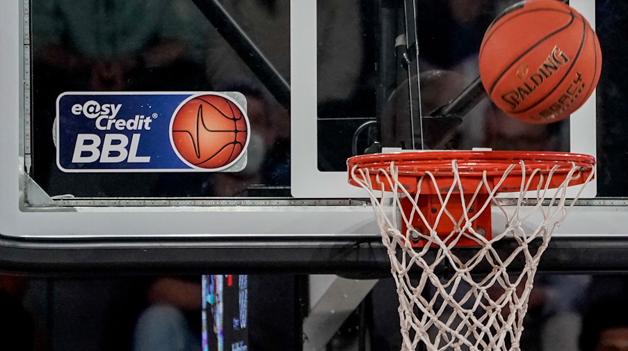Ein Ball fliegt auf den Korb zu, an dem ein Logo der Basketball-Bundesliga klebt. / Foto: Axel Heimken/dpa/Symbolbild