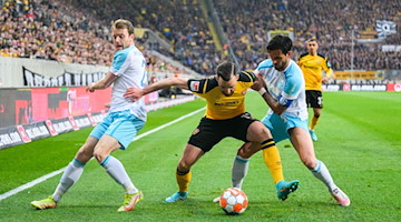 Dynamos Morris Schröter (M) gegen Schalkes Thomas Ouwejan (l) und Danny Latza. / Foto: Robert Michael/dpa