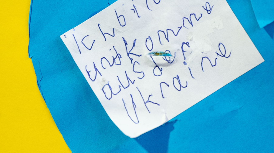 Ein Zettel mit der Aufschrift «Ich bin ... und komme aus der Ukraine» hängt an der Tür einer Schule. / Foto: Marijan Murat/dpa/Symbolbild