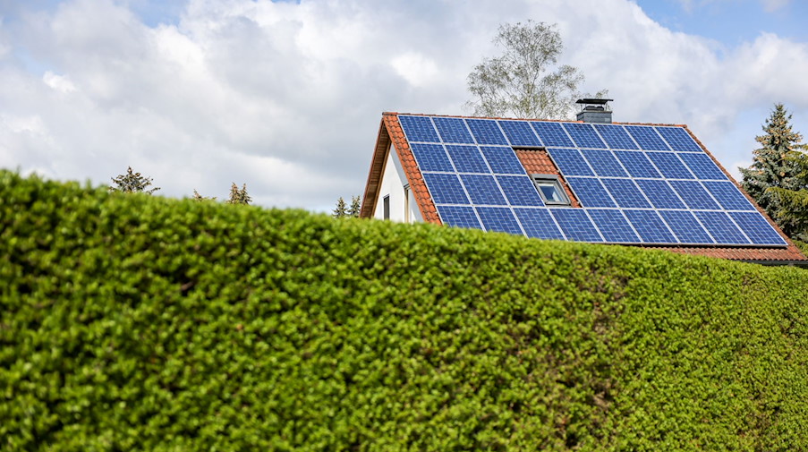 Ein Einfamilienhaus mit Solarzellen auf dem Hausdach steht hinter einer grünen Hecke. / Foto: Jan Woitas/dpa-Zentralbild/dpa/Archivbild