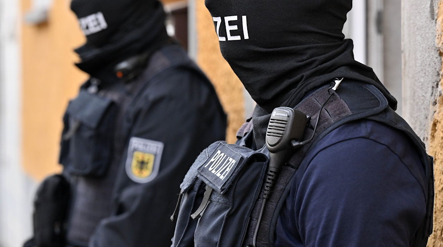 Bundespolizisten stehen vor einem Hauseingang. / Foto: Martin Schutt/dpa
