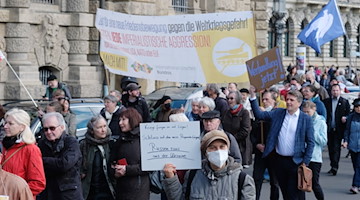 Teilnehmer einer Demonstration gehen mit Fahnen und Transparenten durch das Stadtzentrum. / Foto: Sebastian Willnow/dpa