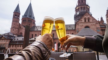 Zwei Gäste stoßen auf der Terrasse mit Bier an. / Foto: Frank Rumpenhorst/dpa/Archivbild