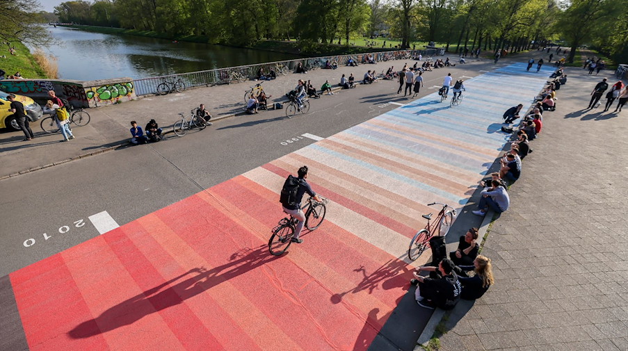 Menschen sitzen neben so genannten "Warming Stripes" auf der Sachsenbrücke. / Foto: Jan Woitas/dpa/Archivbild