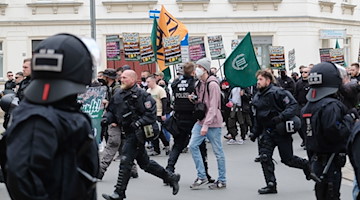 Teilnehmer einer Kundgebung der rechtsextremen Partei „Der dritte Weg“ gehen eine Straße entlang. / Foto: Sebastian Willnow/dpa