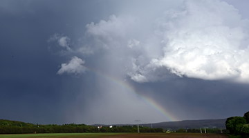 Ein Regenbogen bildet sich vor dunklen Wolken bei Langewiesen. / Foto: Martin Schutt/dpa