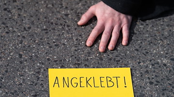 Ein Demonstrant der Gruppe «Letzte Generation» hat sich auf einer Straße festgeklebt. / Foto: Sebastian Gollnow/dpa/Symbolbild