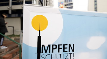 Ein Plakat mit der Aufschrift «Impfen schützt» steht vor einem Impfzentrum. / Foto: Bernd Weißbrod/dpa/Symbolbild