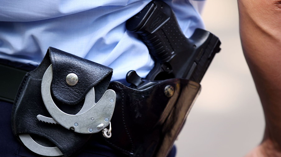 Ein Polizist trägt Handschellen und seine Dienstwaffe bei sich. / Foto: Oliver Berg/dpa/Symbolbild