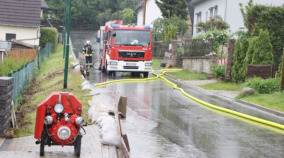 Feuerwehrleute haben auf einer Dorfstraße nach heftigen Regenfällen Pumpen aufgestellt. / Foto: Bodo Schackow/dpa-Zentralbild/dpa/Symbolbild