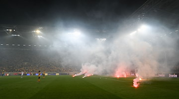 Bengalische Feuer brennen während des Relegationsspiels zwischen dem 1. FC Kaiserslautern und Dynamo Dresden auf dem Rasen des Rudolf-Harbig-Stadion. / Foto: Robert Michael/dpa