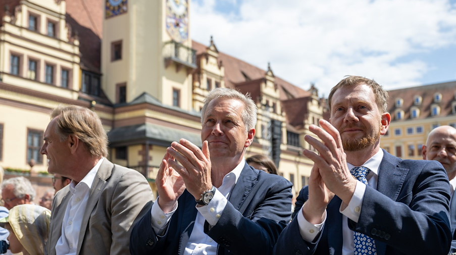 Burkhard Jung (SPD, l-r),Christian Wulff und Michael Kretschmer (CDU) verfolgen die Eröffnung des Deutschen Chorfestes auf dem Markt in Leipzig. / Foto: Hendrik Schmidt/dpa