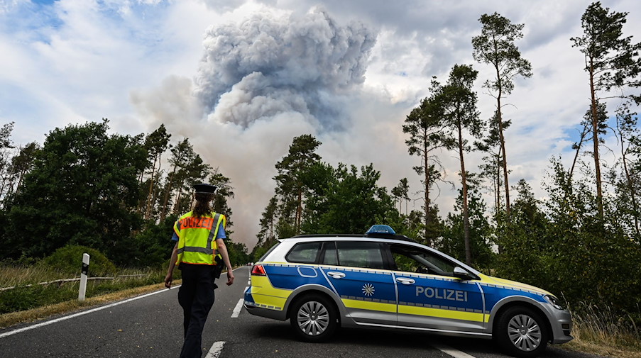 Ein Polizei Auto sperrt die Straße in einem Waldbrandgebiet in der Gohrischheide ab. / Foto: Robert Michael/dpa