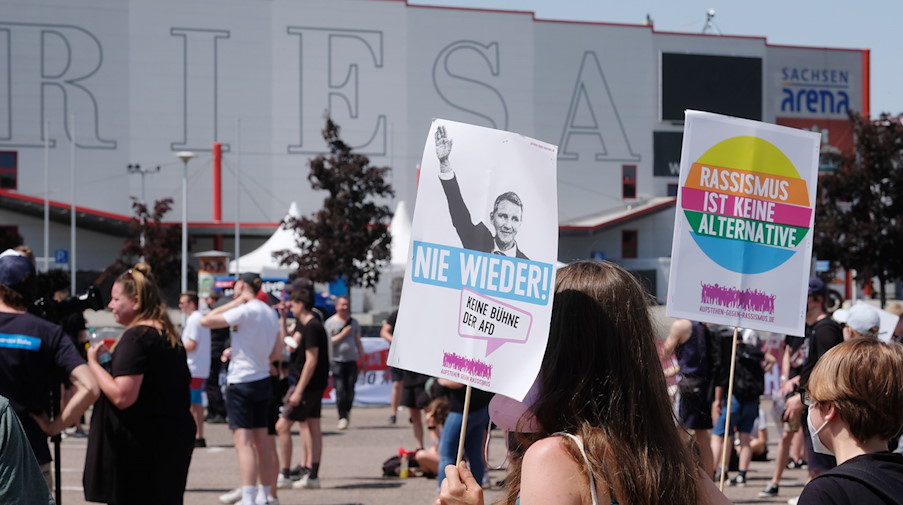 Demosntrantinnen und Demosntranten tragen Schilder mit Aufschriften wie «Keine Bühne der AfD» und «Rassismus ist keine Alternative» vor der Sachsen-Arena. / Foto: Sebastian Willnow/dpa