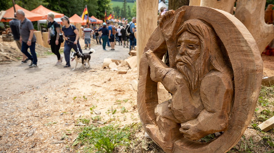 Ein sitzendes Holzmännchen in einem Baumstamm steht auf dem Boden beim 19. Blockhausencup. / Foto: Daniel Schäfer/dpa