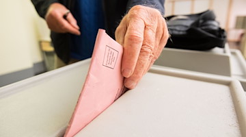 Ein Mann wirft seinen Stimmzettel in eine Urne. / Foto: Julian Stratenschulte/dpa/Symbolbild