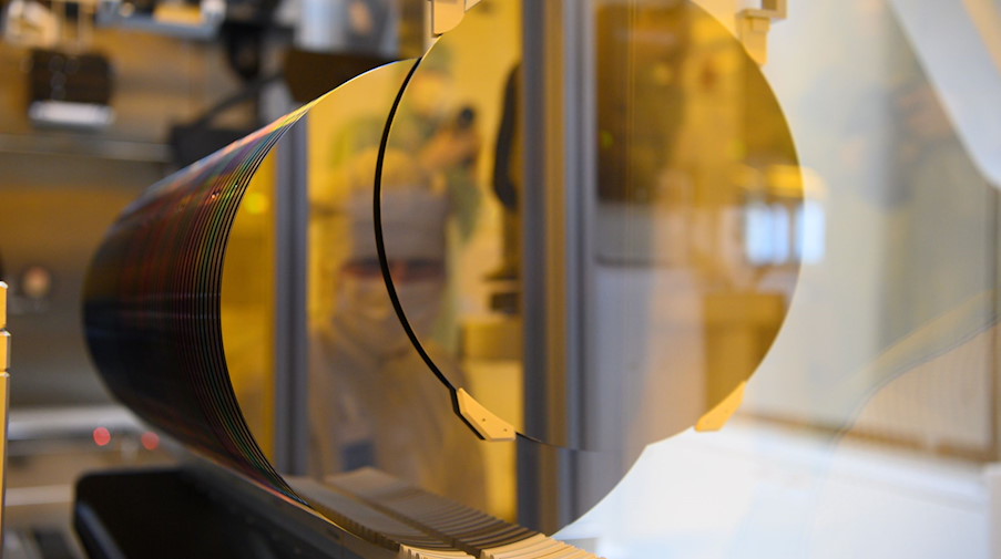 Ein Mitarbeiter spiegelt im Reinraum in einem 300-Millimeter-Wafer. / Foto: Robert Michael/dpa-Zentralbild/dpa/Symbolbild