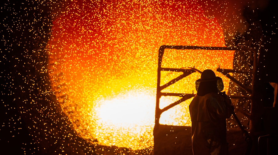 Ein Mitarbeiter reinigt in einem Stahlwerk eine Roheisenpfanne. / Foto: Christophe Gateau/dpa/Symbolbild