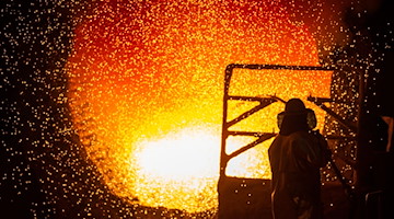 Ein Mitarbeiter reinigt in einem Stahlwerk eine Roheisenpfanne. / Foto: Christophe Gateau/dpa/Symbolbild