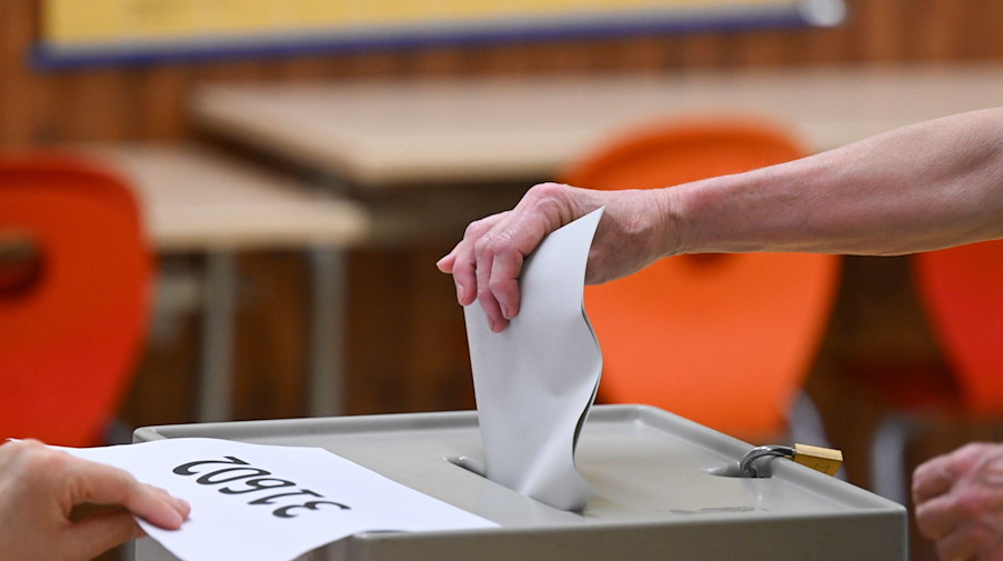 Eine Frau wirft für die Oberbürgermeisterwahl in einem Wahllokal den Stimmzettel in die Wahlurne. / Foto: Robert Michael/dpa