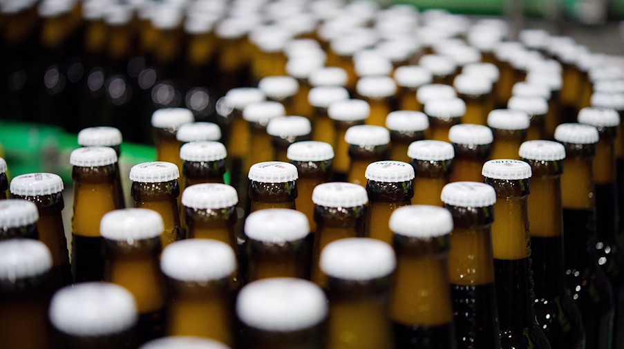 Bierflaschen mit Kronkorken laufen durch die Produktion einer Brauerei über die Förderbänder einer Befüllungsanlage. / Foto: Rainer Jensen/dpa/Symbolbild