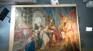 Eine Mitarbeiterin des Finanzministeriums Sachsen begutachtet im Textildepot des Residenzschloss den Wandteppich „Die Ohnmacht der Esther“. / Foto: Sebastian Kahnert/dpa