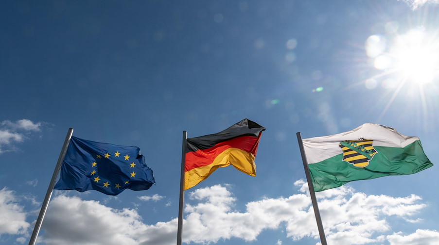 Die Fahnen von Europa (l-r), Deutschland und Sachsen wehen im Wind. / Foto: Robert Michael/dpa-Zentralbild/ZB/Symbolbild