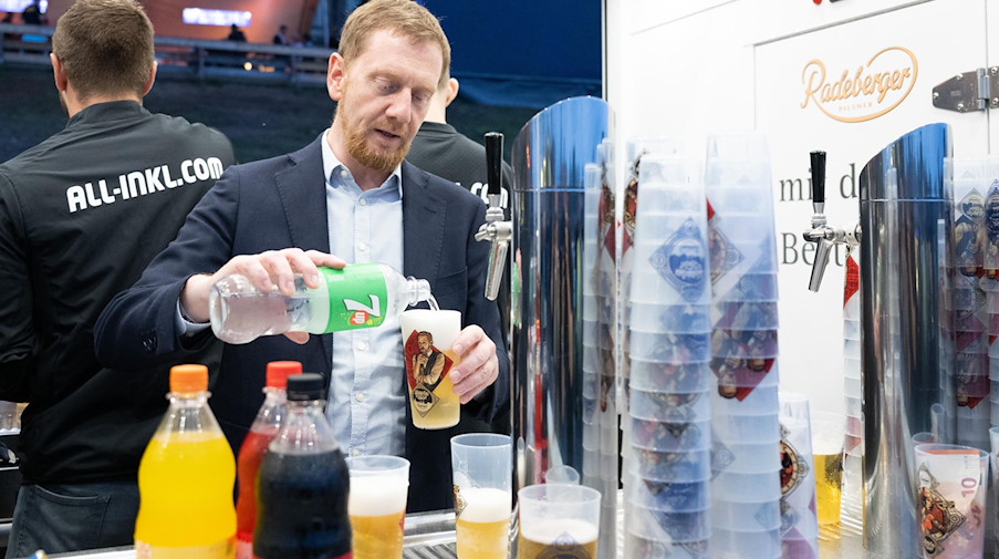 Michael Kretschmer (CDU), Ministerpräsident von Sachsen, schenkt ein Getränk ein. / Foto: Sebastian Kahnert/dpa