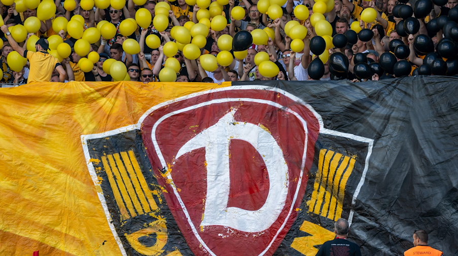Dynamo-Fans halten das Vereinslogo und Luftballons in den Vereinsfarben empor. / Foto: Hendrik Schmidt/dpa/ZB/Archiv