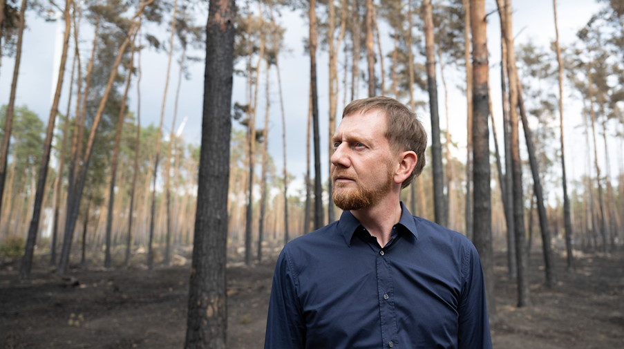 Michael Kretschmer begutachtet die Schäden in einem an Brandenburg angrenzenden Waldbrandgebiet bei Arzberg. / Foto: Sebastian Kahnert/dpa