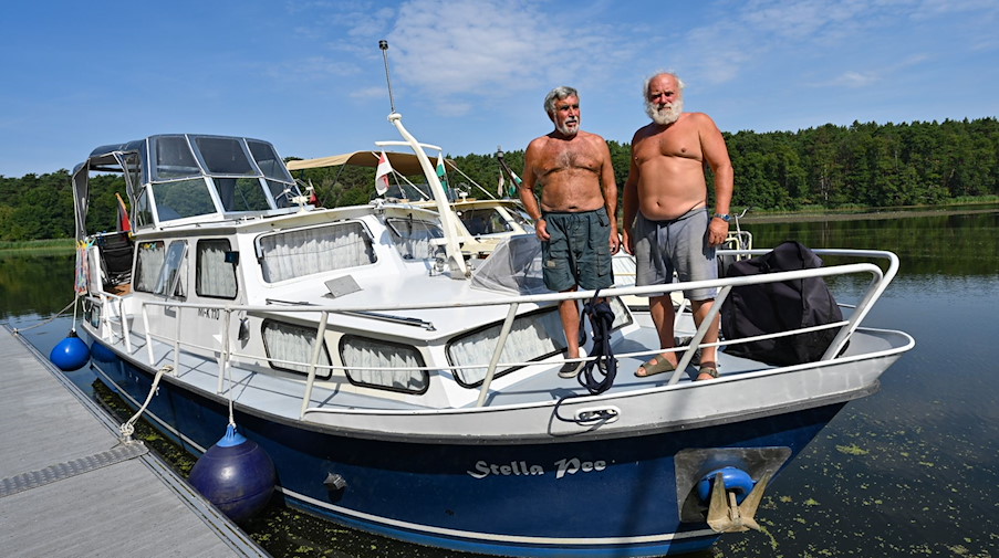 Peter Schneider (l) und Matthias Graupner, Freunde und Rentner, warten auf einem Boot auf der Spree vor der geschlossenen Kersdorfer Schleuse auf die Einfahrt zum Oder-Spree-Kanal. / Foto: Patrick Pleul/dpa