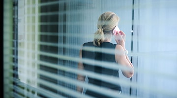 Eine Frau steht in einem Büro und telefoniert. / Foto: Annette Riedl/dpa/Illustration