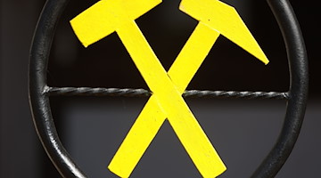Zwei gekreuzte Hämmer bilden das Bergmannsymbol an einem Tor. / Foto: Matthias Bein/dpa/Symbolbild
