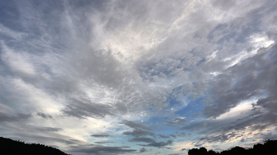 Eine aufreißende Wolkendecke zieht über eine Wiese hinweg. / Foto: Thomas Frey/dpa/Symbolbild