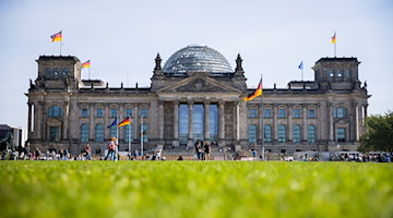 Vor und auf dem Reichstagsgebäude wehen Deutschlandfahnen. / Foto: Christoph Soeder/dpa/Archivbild