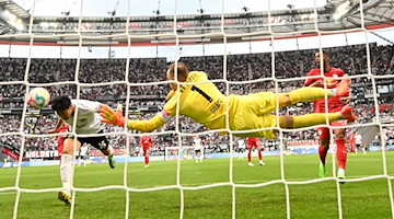 Frankfurts Daichi Kamada (l) erzielt das Tor zum 1:0 gegen Leipzigs Torwart Peter Gulacsi. / Foto: Arne Dedert/dpa