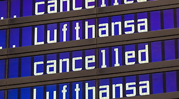 Anzeigentafeln zeigen «cancelled» und «Lufthansa» am Flughafen München an. / Foto: Peter Kneffel/dpa/Symbolbild